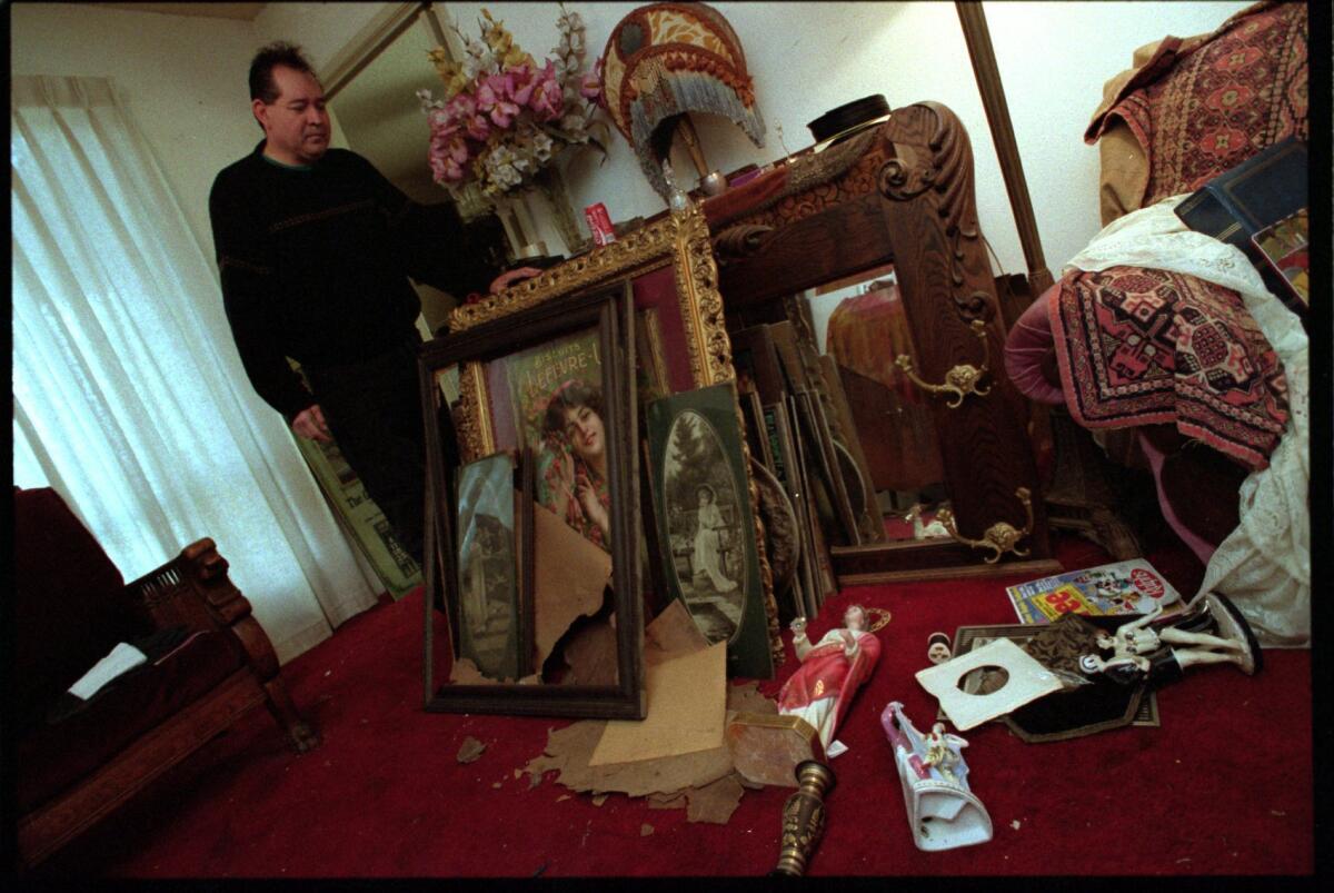Rick Olguin of Lake View Terrace stands next to rare Victorian paintings from his collection after the 1994 Northridge earthquake. About 50 were damaged in the quake. (Ricardo DeAratanha / Los Angeles Times)