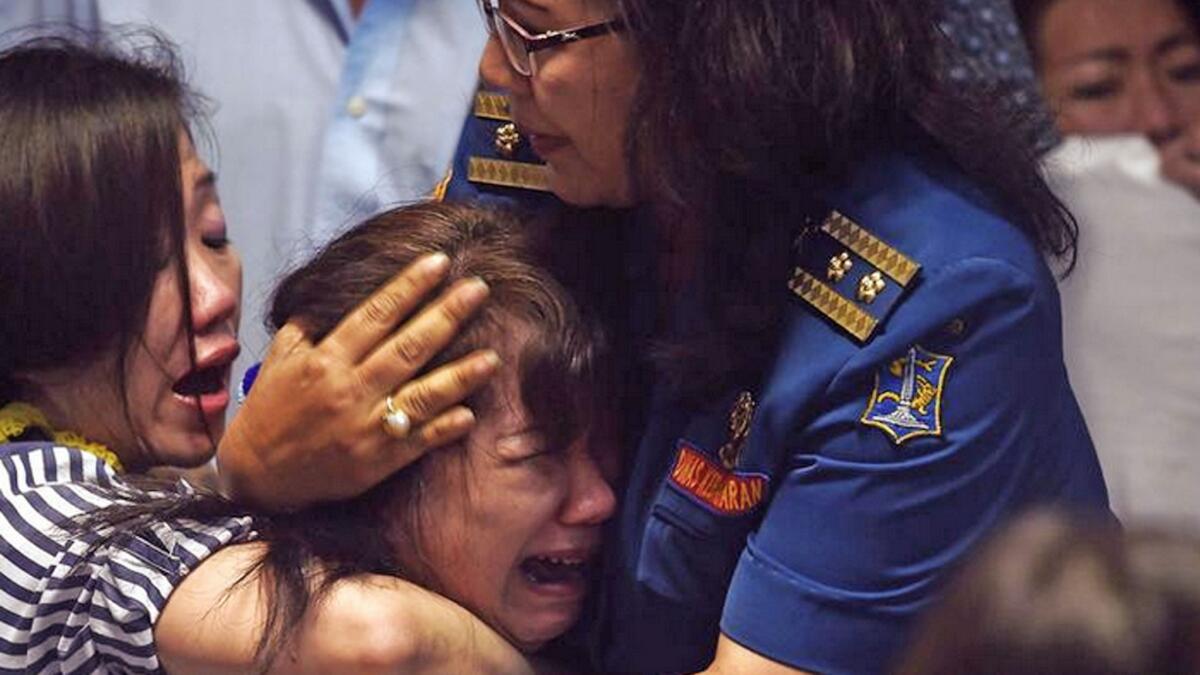 Family members of missing passengers react after watching news reports showing a body floating in the Java Sea.