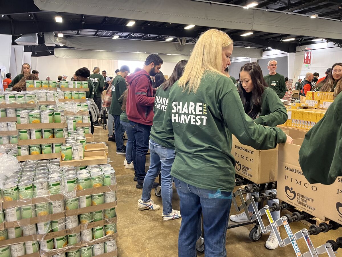 Employees of Newport Beach-based company PIMCO pack boxes with food and goods.