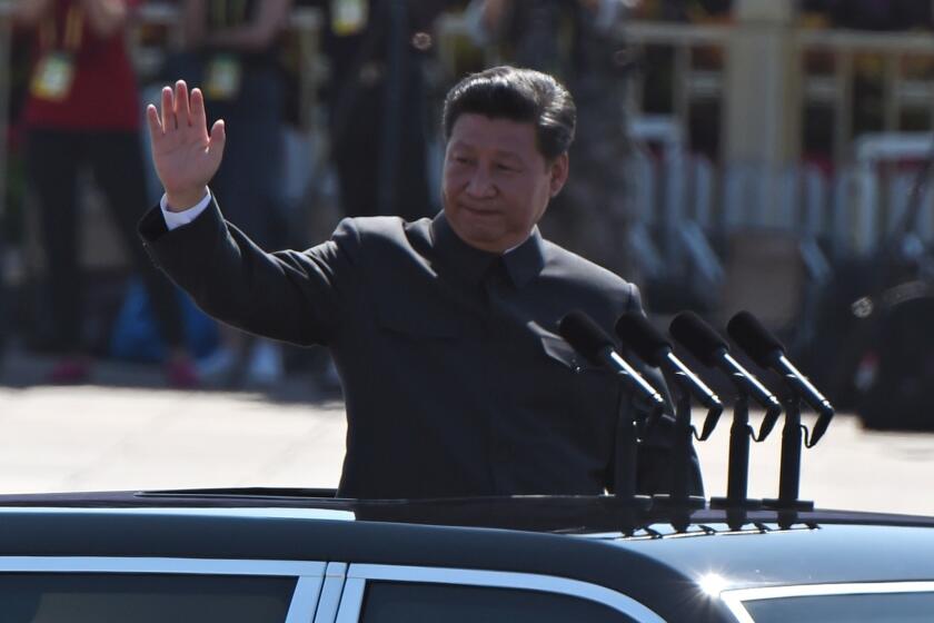 Chinese President Xi Jinping waves as he reviews troops from a car during a military parade at Tiananmen Square in Beijing.