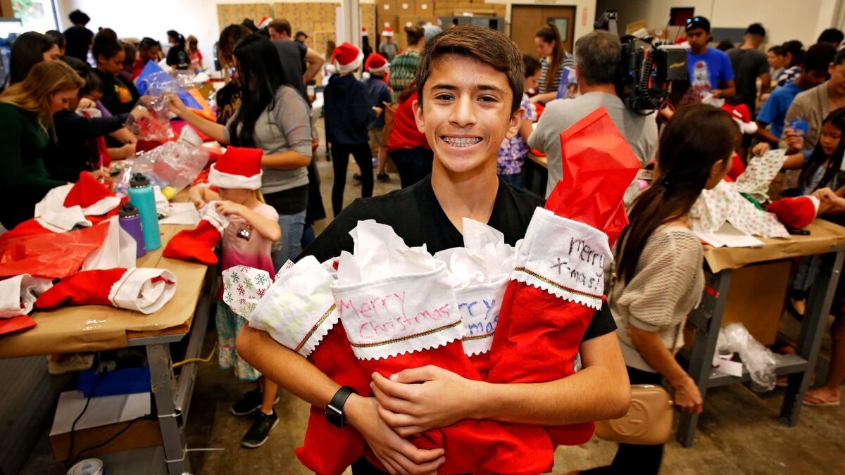 Kenan Pala, 13, of Rancho Bernardo with some of the Christmas stockings stuffed with donated toys and personal items Sunday by volunteers with his nonprofit group Kids 4 Community.