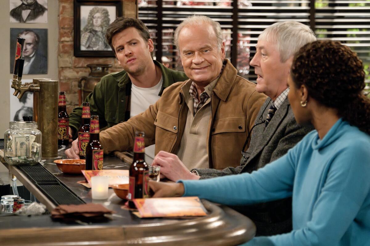 Three men and a woman sit in a bar with beers in a scene from the new "Frasier."