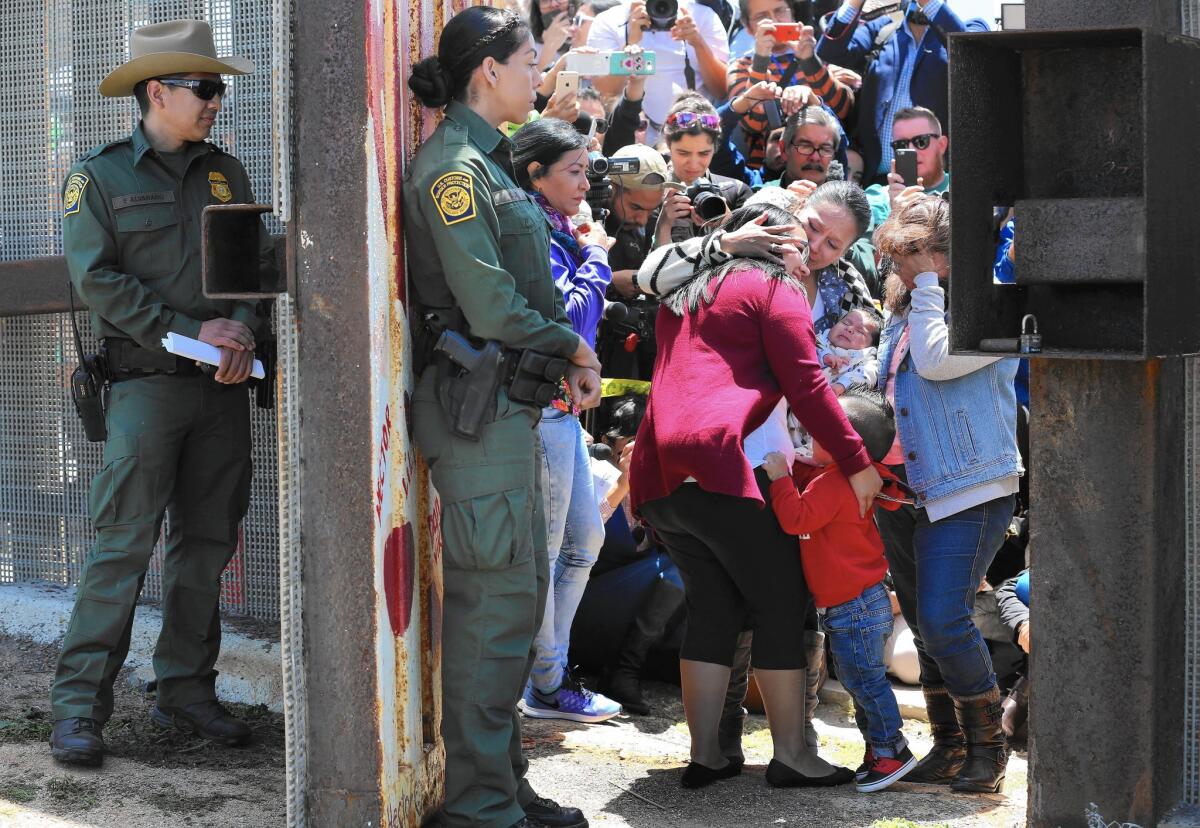 Border Patrol agents watch as members of selected families that have been separated for years reunite — however briefly — at the Door of Hope at Border Field State Park near San Diego. This is the third year for Children’s Day.