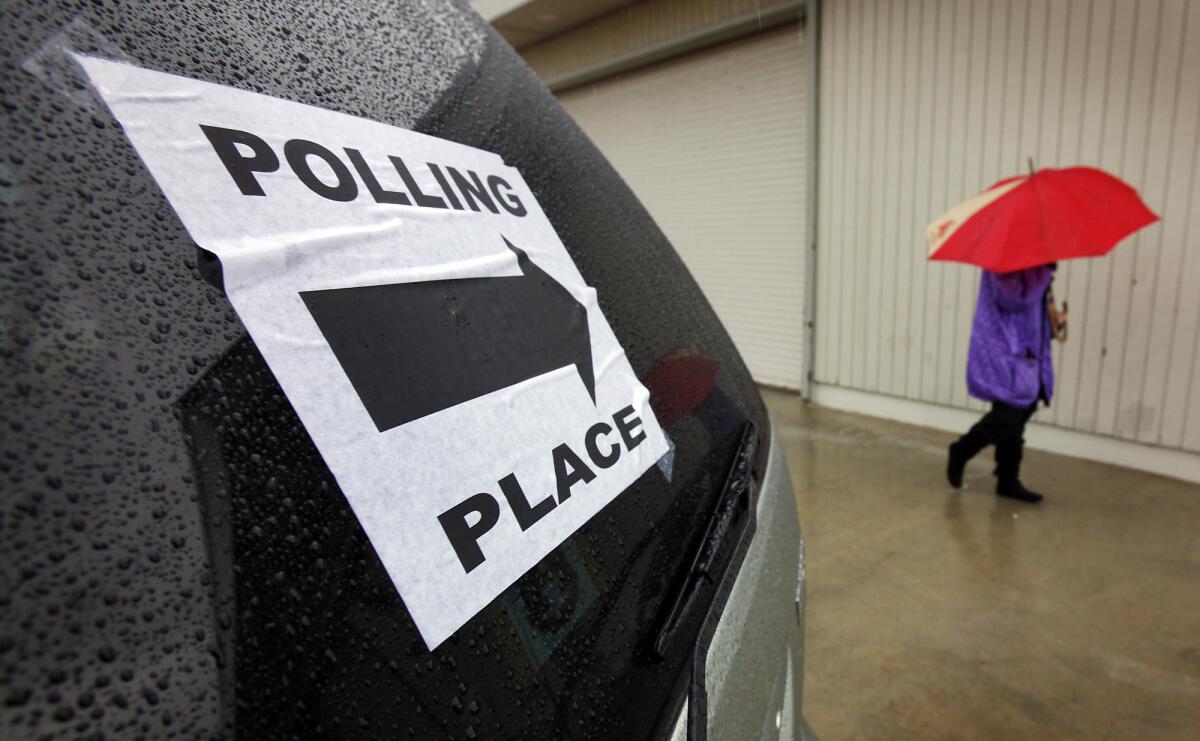 A voter uses her umbrella in the rain after voting at the L.A. County Lifeguard Headquarters polling location in Venice.