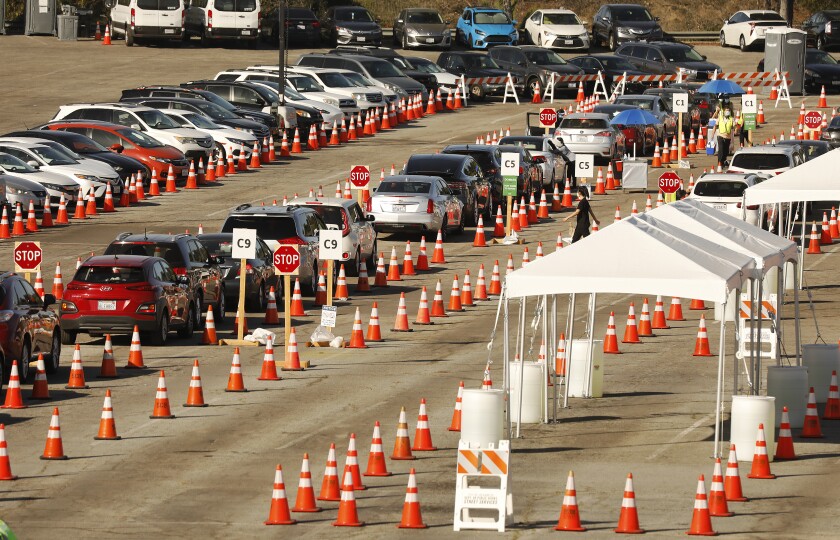 Vehicles wind their way through the parking lot at Dodger Stadium for COVID-19 vaccinations.