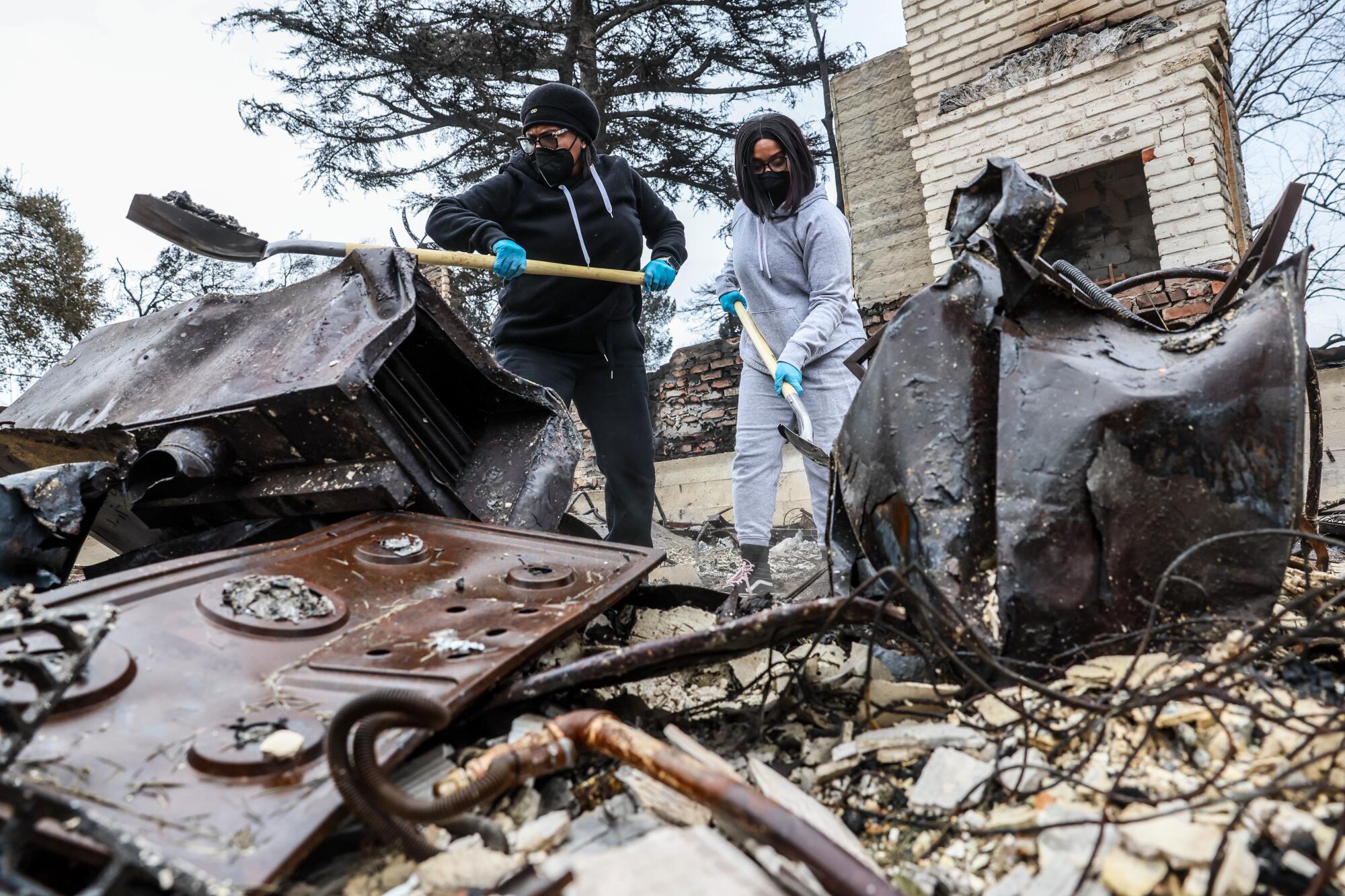 A mother and daughter dig through rubble.