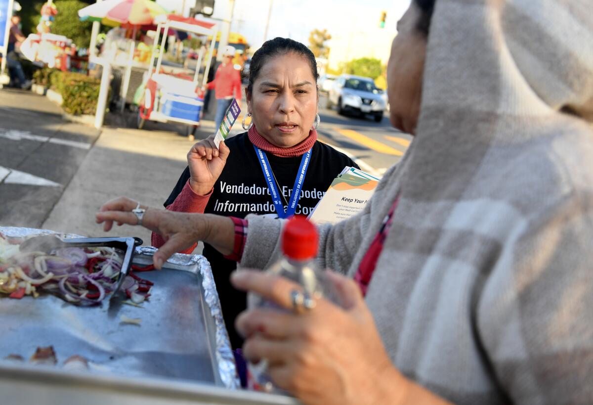 Juana Dominguez hands out information about Medi-Cal along Main Street in South Los Angeles.