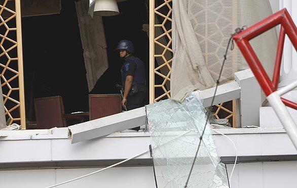 A police bomb squad member inspects the damage from the blast at the Ritz-Carlton hotel in Jakarta, Indonesia.