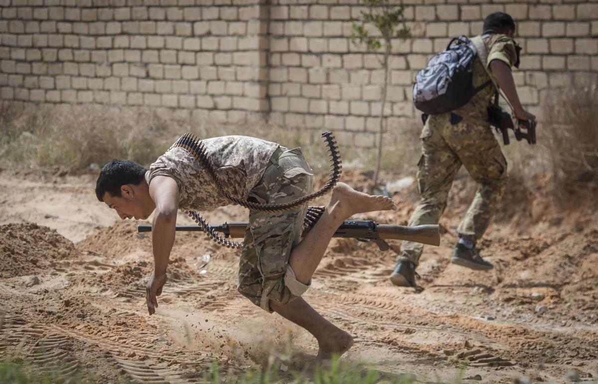 Fighters loyal to the Government of National Accord run for cover during clashes with forces loyal to strongman Khalifa Haftar south of Libya's capital, Tripoli, in April.  