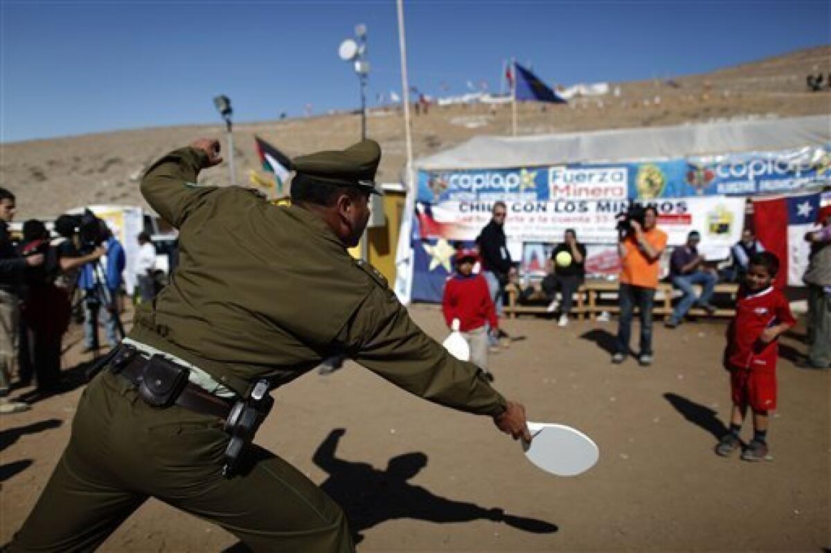 A police officer plays racquet ball with children, relatives of trapped, miners at the San Jose Mine, near Copiapo, Chile, Tuesday, Oct. 12, 2010. Andres Sougarett, the Chilean engineer leading the rescue effort, said all would be in place at midnight Tuesday to begin the rescue of the miners. (AP Photo/Natacha Pisarenko)