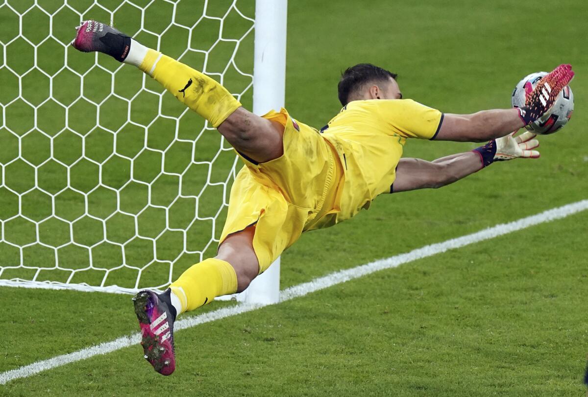 Italy goalkeeper Gianluigi Donnarumma makes a save on England's Jadon Sancho during the penalty shoot out following the Euro 2020 soccer championship final match between England and Italy at Wembley Stadium in London, Sunday, July 11, 2021. (Mike Egerton/PA via AP)