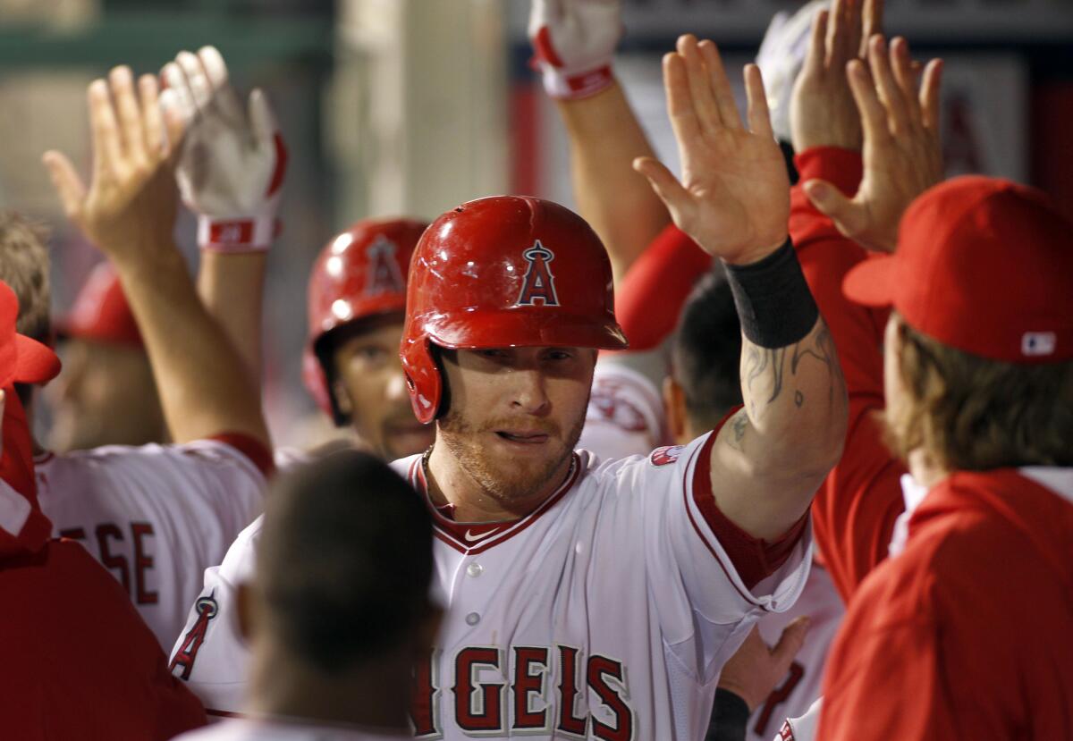 The Angels' Josh Hamilton, center, is congratulated in the Angel Stadium dugout after scoring against the Mariners on April 1, 2014.