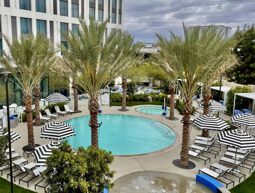 A round pool surrounded by palm trees and striped umbrellas