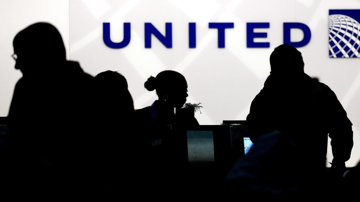 Holiday travelers check in at the United Airlines ticket counter at O'Hare International Airport in Chicago. The airline plans to offer some passengers cash to give up their seats for travelers who are willing to pay more.