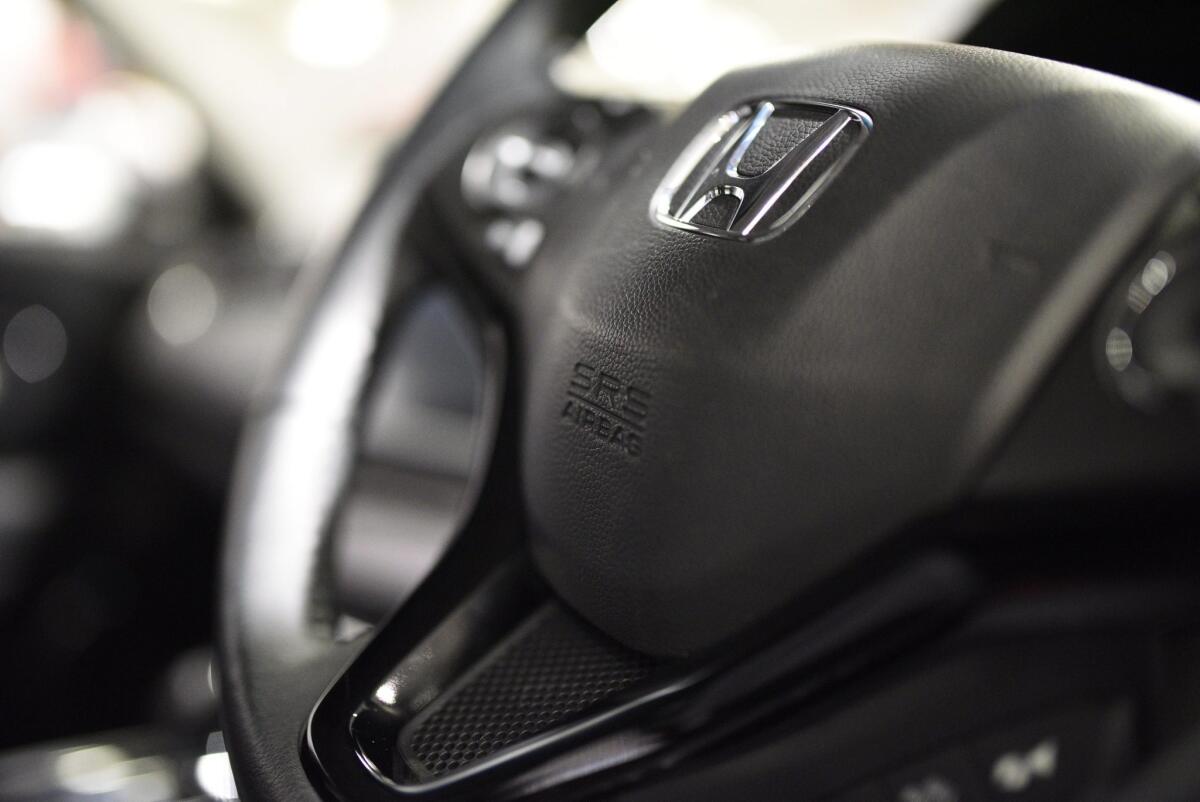 An SRS air bag logo is seen on the steering wheel of a Honda vehicle. Safety regulators fined Honda for not properly reporting problems with defective air bags and other defects.