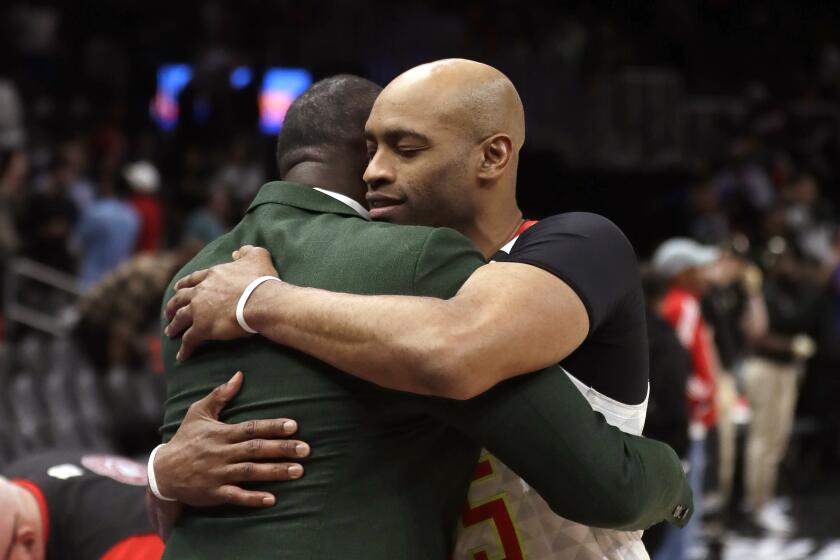 Atlanta Hawks guard Vince Carter, right, hugs former Hawk Dominique Wilkins as he leaves the court following an NBA basketball game against the New York Knicks Wednesday, March 11, 2020, in Atlanta. (AP Photo/John Bazemore)