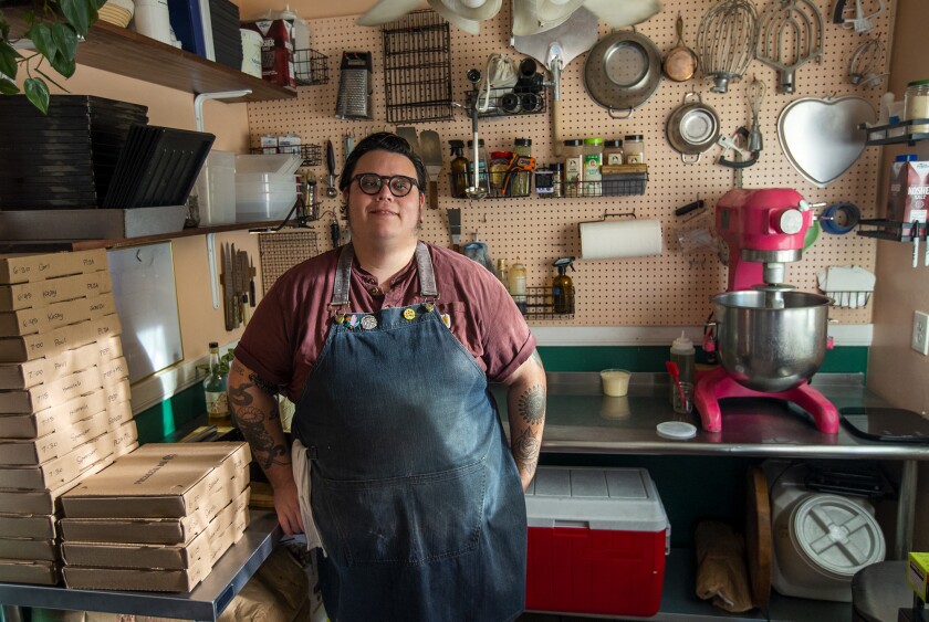 Derek Bracho stands with to-go boxes in the kitchen where he makes homemade focaccia-bread pizza at his home in Anaheim.