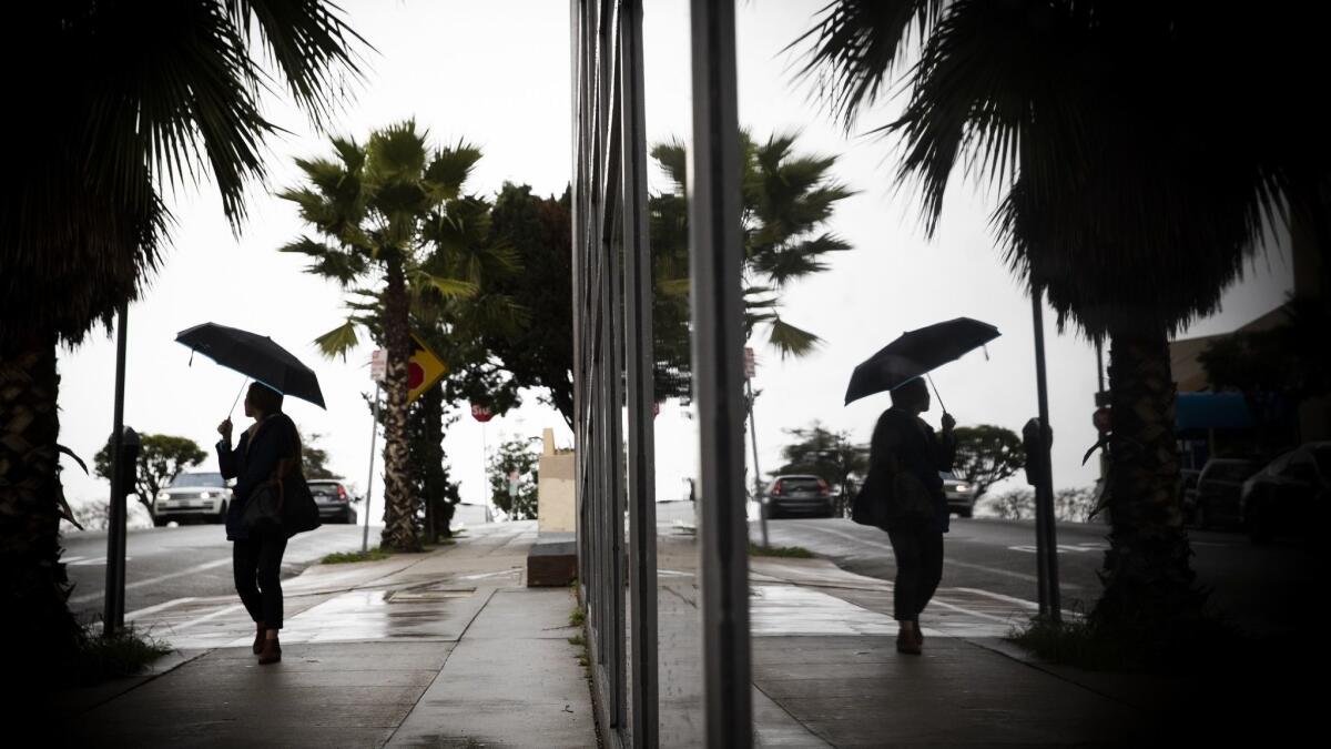 A pedestrian is reflected in a window along a sidewalk in Los Angeles during the last series of storms in January.