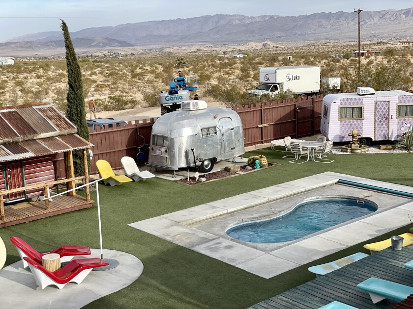 Vintage trailers surround a small swimming pool. 