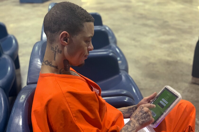 In a photo provided by the North Fork Correctional Center in Sayre, Oklahoma on Tuesday, June 9, 2021, inmate Byron Robinson works on a new Securus tablet, which are being provided for free to Oklahoma inmates as part of a new program by the Department of Corrections. Robinson, who has been incarcerated since 2005, the same year YouTube was founded, said it was the first time he'd ever held a computer tablet. The devices will include free content like access to a law library, along with some podcasts, books and educational materials. (Lance West/Oklahoma Department of Corrections via AP)