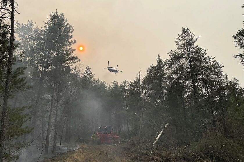 Esta imagen proporcionada por el Departamento de Recursos Naturales de Michigan muestra personal de emergencia, una aeronave y equipo pesado usado en el combate de un incendio forestal cerca de Grayling, Michigan, el 3 de junio de 2023, (Departamento de Recursos Naturales de Michigan vía AP)