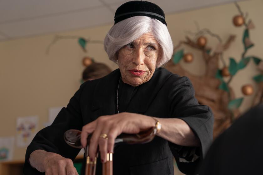 An elderly woman in black has a vulnerable expression.