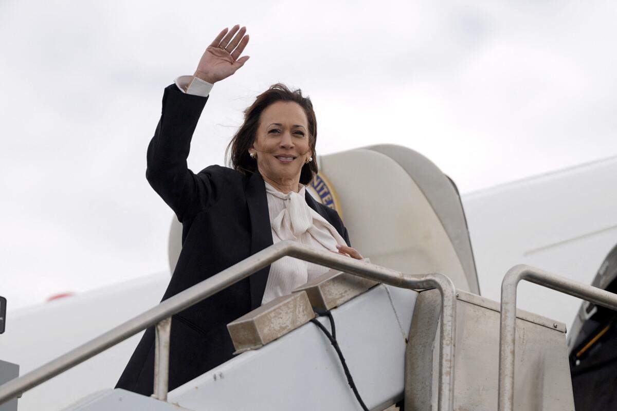 Kamala Harris waving as she enters a plane