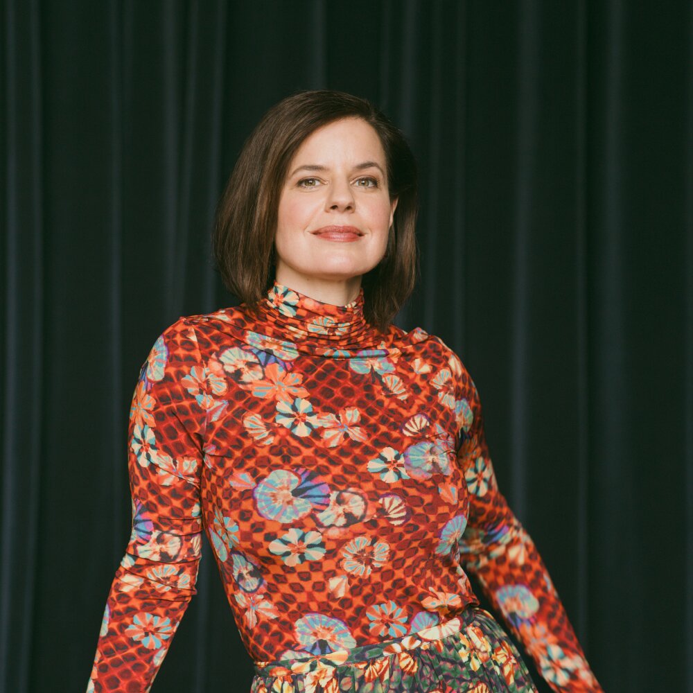 A smiling woman in a brightly patterned shirt poses for a portrait