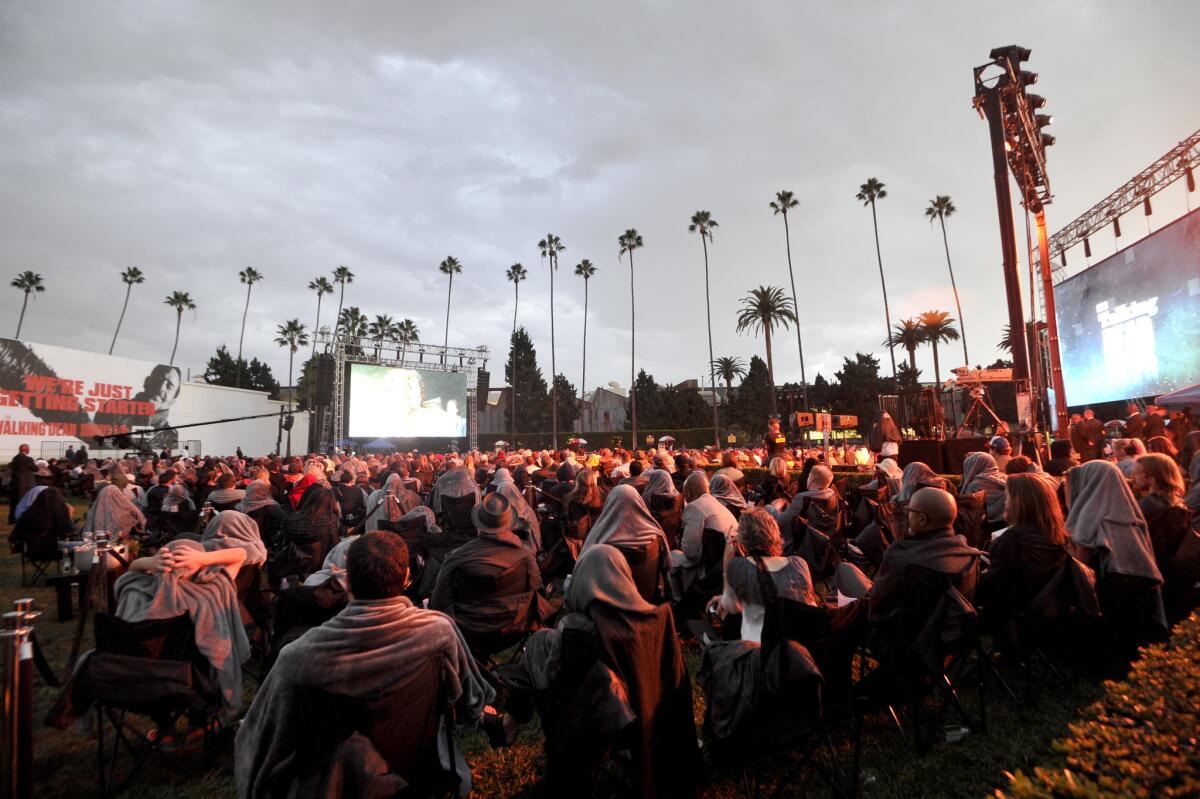 Fans of "The Walking Dead" brave the rain to watch the season premiere at Hollywood Forever Cemetery as part of a "Talking Dead Live" event.