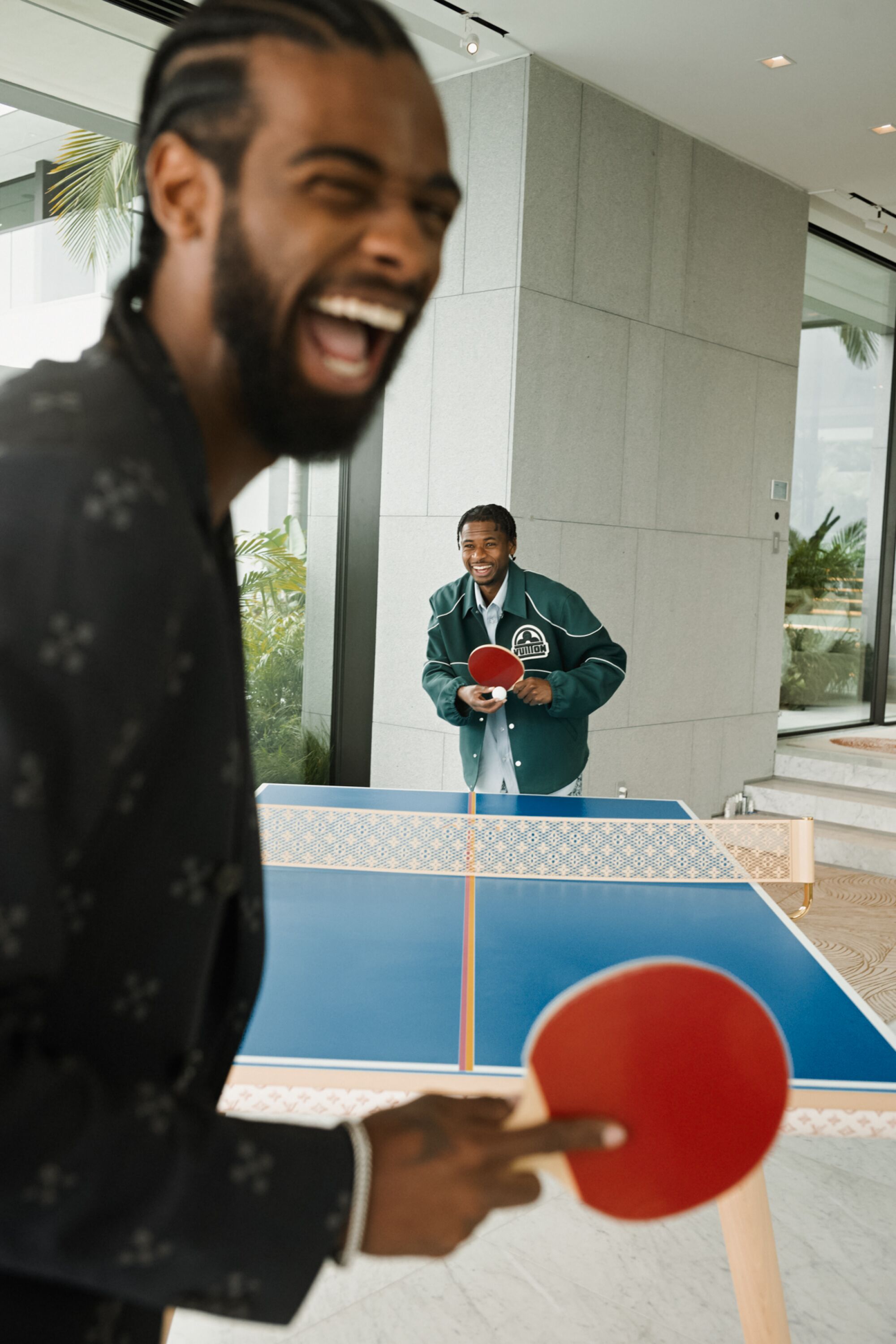 Two people laugh and play ping pong.