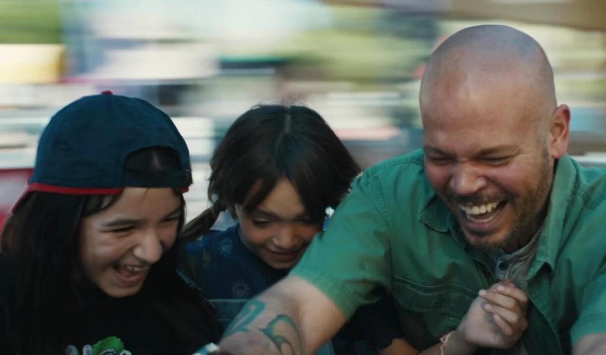 A man and two young children laugh on a whirling ride.