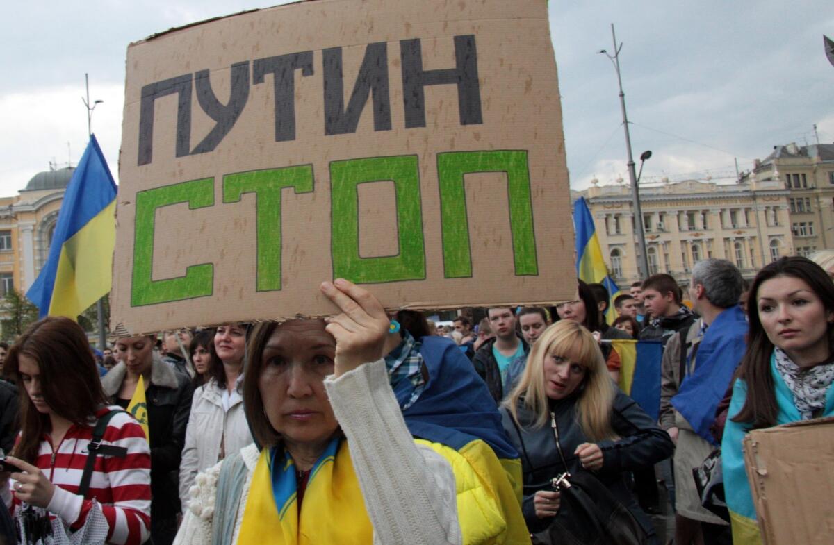 A woman draped in the Ukrainian flag hoists a sign urging "Putin Stop" during a rally this week that drew 2,000 to show their support for Ukrainian unity in Kharkiv, Ukraine's second-largest city, which has a large Russian minority.