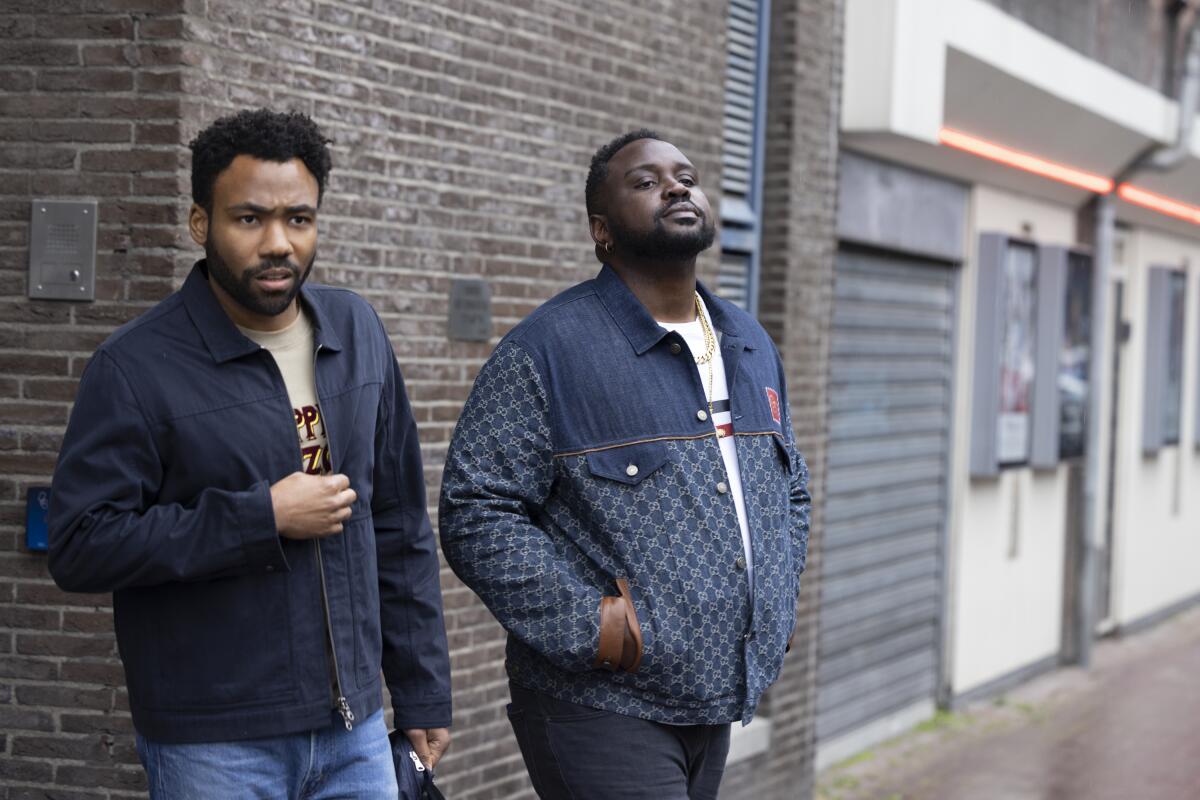 Two men standing on the sidewalk outside a brick building.