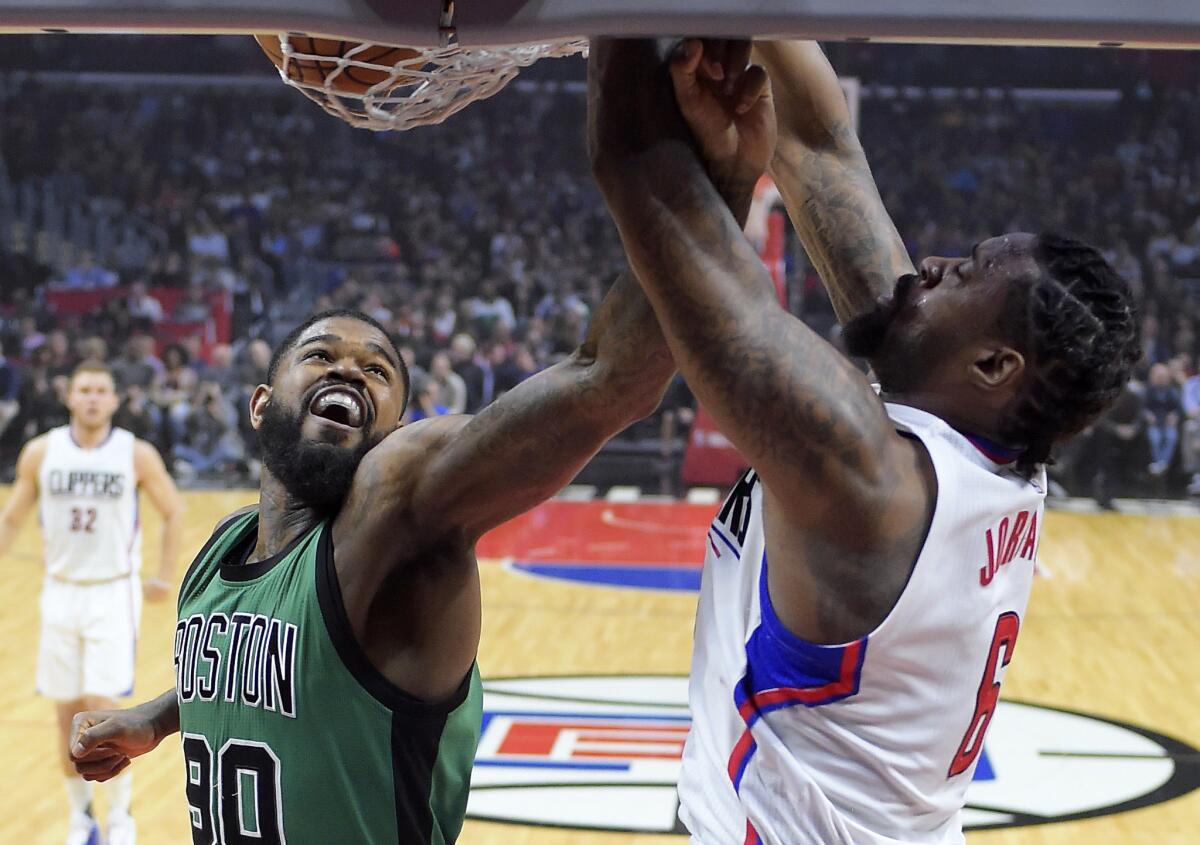 El jugador de los Clippers de Los Ángeles DeAndre Jordanhace un mate defendido por su rival de los Celtics de Boston Amir Johnson, en la primera mitad del juego de la NBA que enfrentó a ambos equipos, el 6 de marzo de 2017, en Los Ángeles.