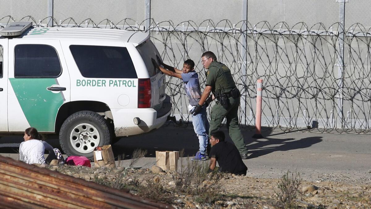 Honduran asylum seekers are taken into custody by Border Patrol agents after crossing over the U.S. border wall in San Diego in December.