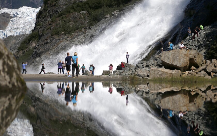 FILE - In this July 31, 2013, file photo, tourists visiting the Mendenhall Glacier in the Tongass National Forest are reflected in a pool of water as they make their way to Nugget Falls in Juneau, Alaska. The Biden administration said Thursday, July 15, 2021, that it is ending large-scale, old-growth timber sales on the nation's largest national forest, the Tongass National Forest in Alaska, and will instead focus on forest restoration, recreation and other non-commercial uses. (AP Photo/Charles Rex Arbogast, File)