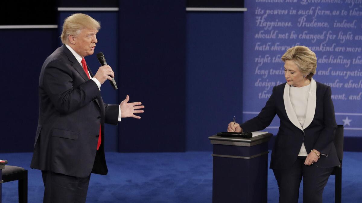 Republican presidential nominee Donald Trump speaks while Democratic presidential nominee Hillary Clinton takes notes.