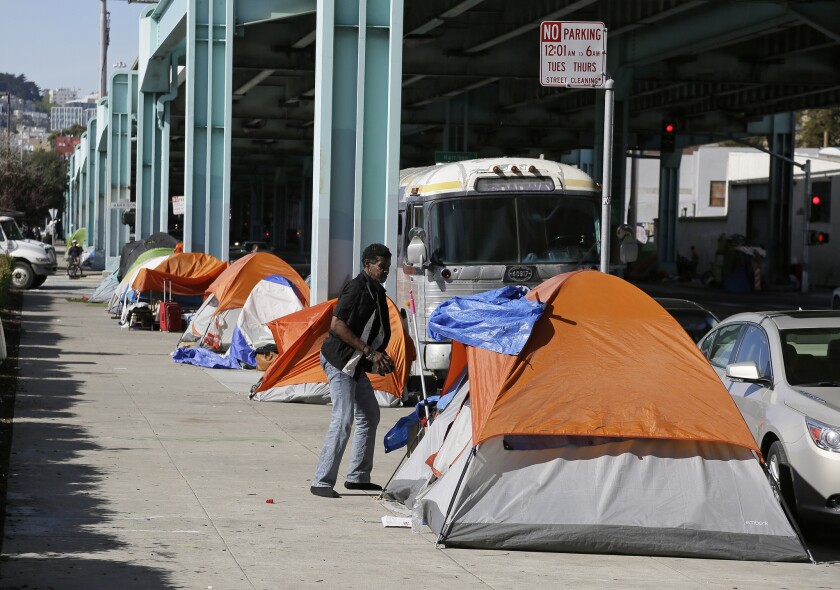In this Feb. 23, 2016 file photo, a man stands outside his tent on Division Street in San Francisco. San Francisco voters will decide in November 2018 whether to tax large businesses to pay for homeless and housing services in a city struggling with income inequality.