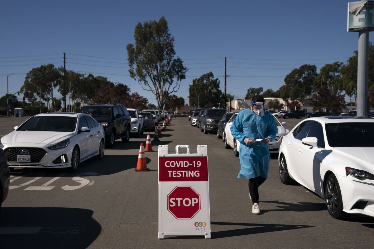 FILE - In this Nov. 16, 2020, file photo, student nurse Ryan Eachus collects forms as cars line up for COVID-19 testing at a testing site set at the Orange County Fairgrounds in Costa Mesa, Calif. California reported more than 20,000 new coronavirus cases on Wednesday, Dec. 2, 2020, shattering the previous record of 18,350 cases just a week ago. Overall, California has reported more than 1.2 million COVID-19 cases and more than 19,300 deaths. (AP Photo/Jae C. Hong, File)