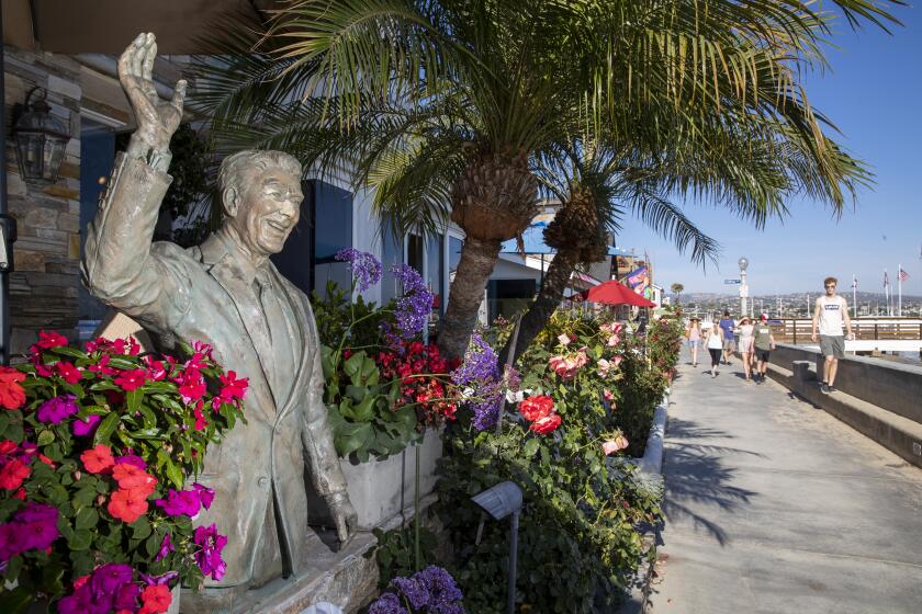 NEWPORT BEACH, CALIF. -- MONDAY, AUGUST 5, 2019: Pedestrians walk past a statue of former President Ronald Reagan at a bay-front home on Balboa Island, Newport Beach Monday, Aug. 5, 2019. (Allen J. Schaben / Los Angeles Times)