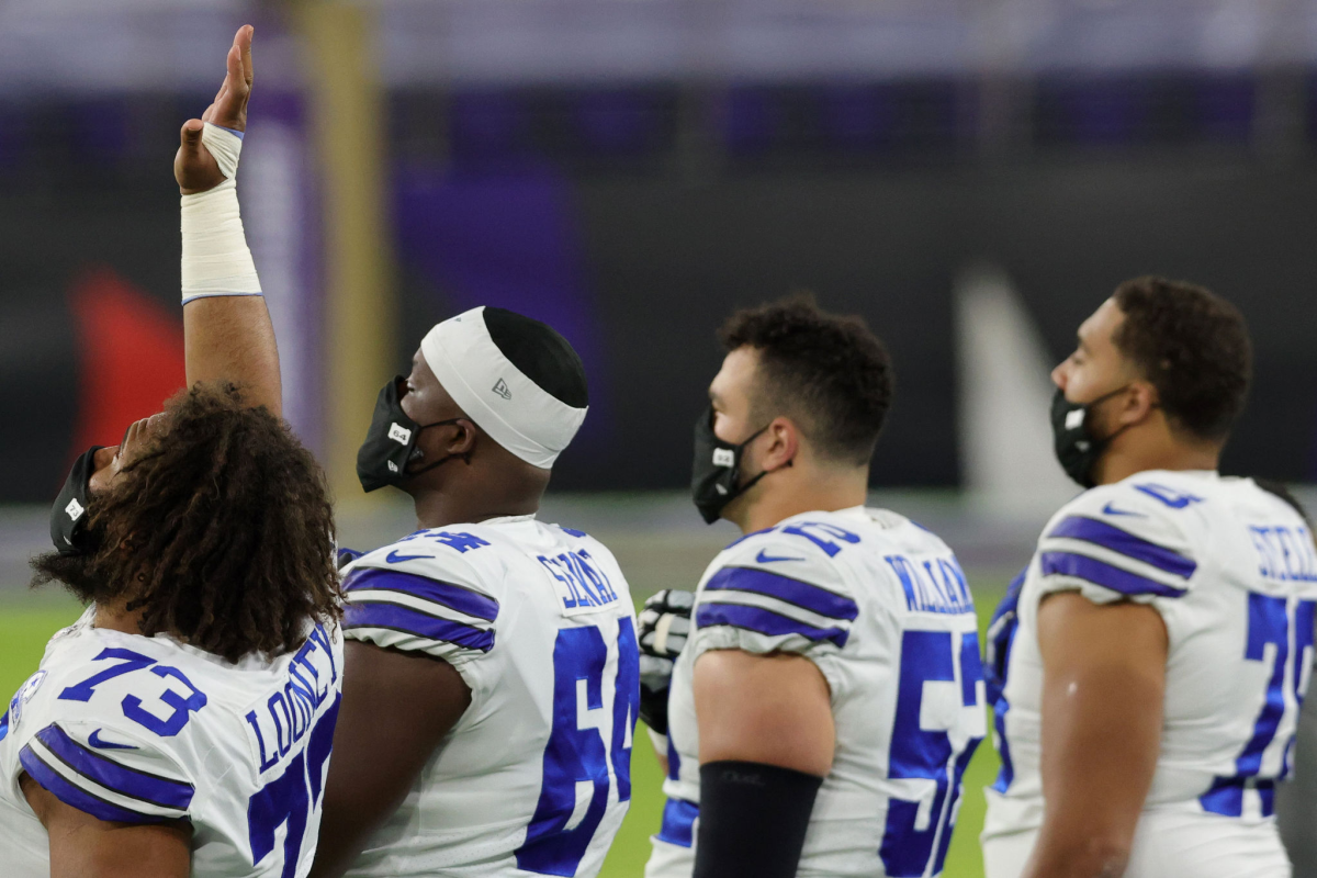 Dallas Cowboy Joe Looney raises his hand into the air during the national anthem before a game against the Baltimore Ravens.