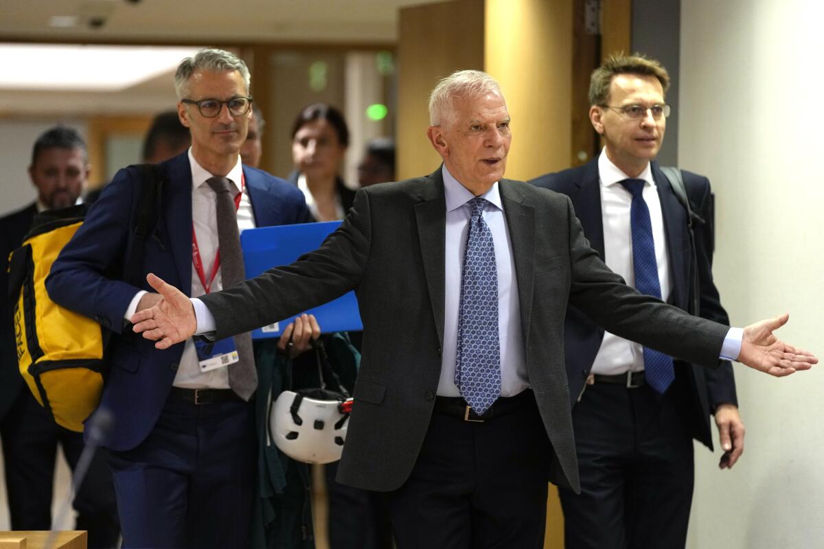 Josep Borrell walks into a meeting with outstretched arms.