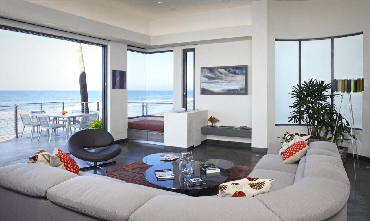 Floor to ceiling windows show the balcony and ocean beyond.