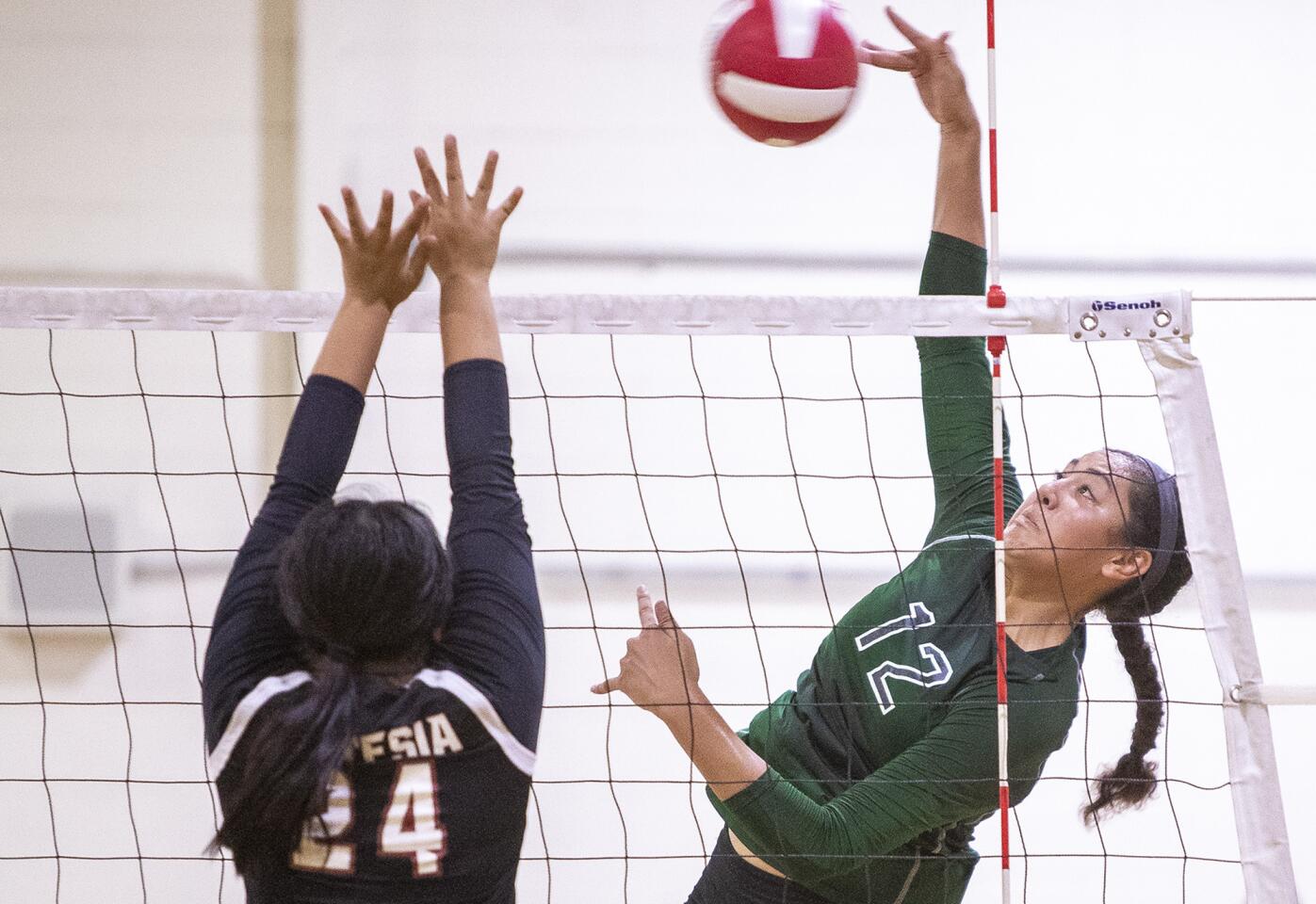 Costa Mesa's Malia Tufuga hits against Artesia's defender Tiffany Ramos during a tournament in Santa Ana on Friday, August 17.