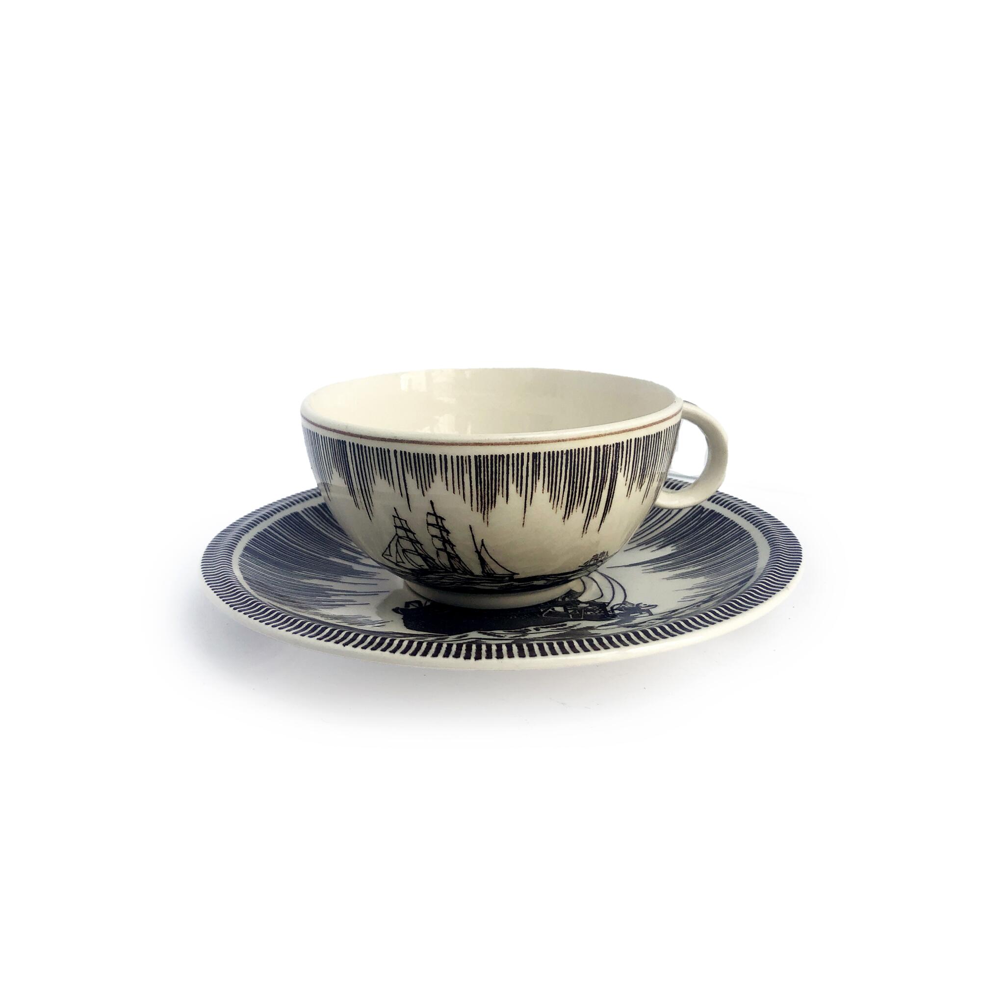 A teacup and saucer with a black and white design