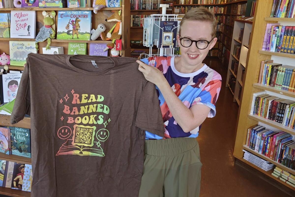 Summer Boismier holds up a T-shirt with a QR code link to the Brooklyn Public Library at a bookstore.