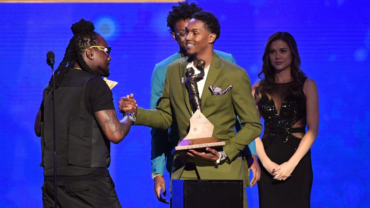 Lou Williams accepts the NBA Sixth Man of the Year award from rapper Wale on stage during the NBA Awards at Barker Hangar on June 24, 2019, in Santa Monica.