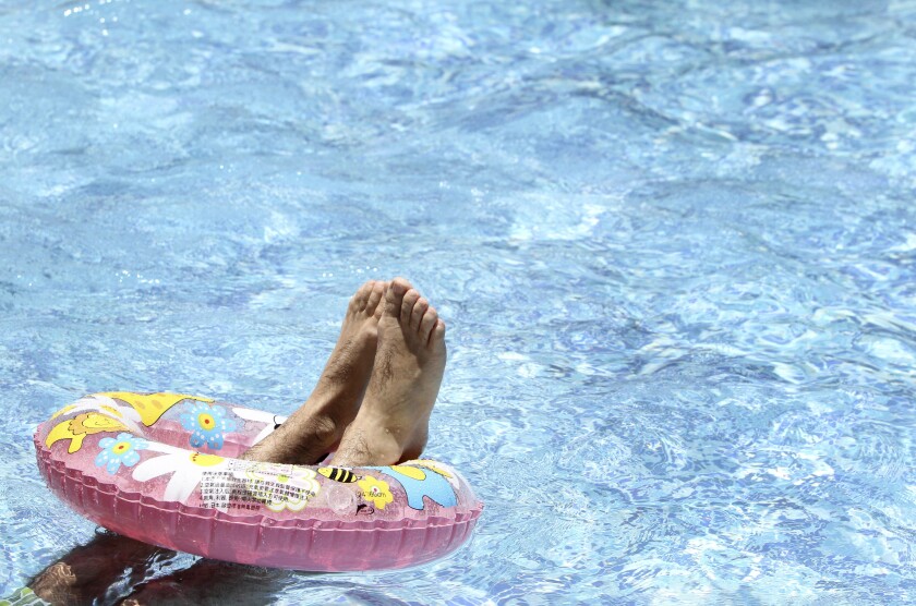 Feet rest in an inner tube floating in a swimming pool.