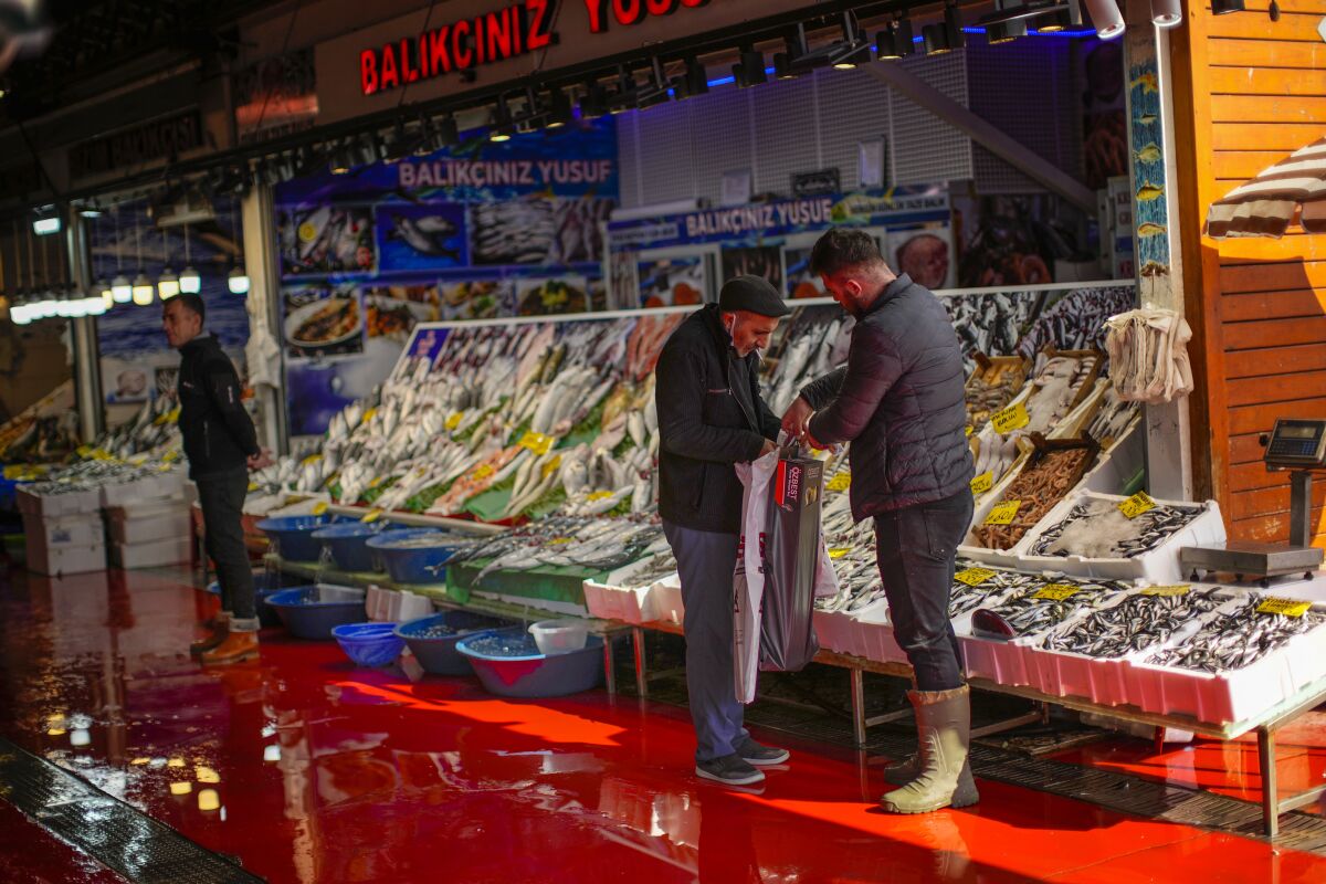 A fishmonger talks to a client at Karakoy fish market in Istanbul, Turkey, Thursday, Oct. 14, 2021. The Turkish lira hit new record lows against the dollar on Thursday after President Recep Tayyip Erdogan sacked senior central bank officials, heightening concerns over the Turkish leader's interference in the bank's activities. (AP Photo/Francisco Seco)