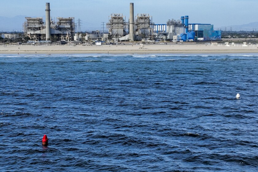 Huntington Beach, CA - April 5: Two buoys mark the location of intake and outflow pipes currently used by the AES Huntington Beach Energy Center, and is the proposed site of the Poseidon Desalination Plant, which would draw ocean water through the existing intake pipe. In the background is neighboring residential community, Edison Community Park, Edison High School, ASCON toxic State superfund cleanup site, the proposed Magnolia Tank Farm Lodge, restaurants, and retail, upper right, the Huntington Beach Wetlands, middle right, and Huntington State Beach. Photo taken Tuesday, April 5, 2022. The partially retired Huntington Beach Generating Station consists of four generating units but only unit 2 is still in commercial operation as a legacy unit and has an extension to operate through the end of 2023, issued by the California State Water Boards. Unit 2 runs to support peak demands and has a net output capacity of 225 megawatts. The 644 MW combined cycle gas turbine generator, shown in blue and white, began operation on June 25, 2020. Environmental groups have fought Poseidon, arguing that it is privatizing a public resource, has failed to adapt an old proposal to new state ocean protections from killing sea life and that the company is trying to fill a need that doesn't exist, uses too much natural gas energy. Environmental justice activists say water rates could be raised as much as $6 per month. Supporters say ocean desalination as an inexhaustible, local supply for a region that imports much of its water from increasingly unreliable, distant sources. Another stumbling block for Poseidon is state requirements to mitigate the project's harm to the marine environment. Poseidon would draw 106 million gallons a day of seawater through the huge offshore intake pipe, which would be screened, and use reverse osmosis membranes to rid the seawater of salt and impurities. That process would produce 56 million gallons a day of brine concentrate - roughly twice as salty as the ocean - which would be dumped back into the Pacific via a 1,500-foot discharge pipe equipped with outfall diffusers to promote mixing and dilution. The intake and discharge operations will take a toll on plankton, which plays a crucial role in the marine food chain, killing an estimated 300,000 microscopic organisms a day. (Allen J. Schaben / Los Angeles Times)